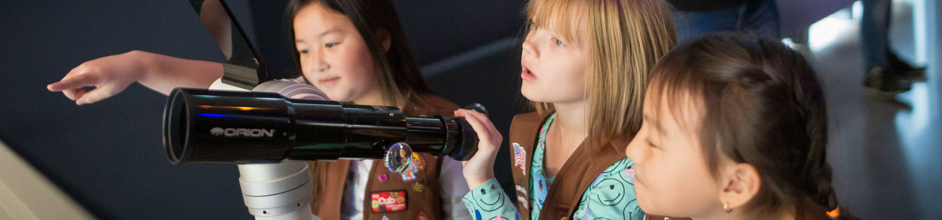  Brownie Girl Scouts using a telescope 