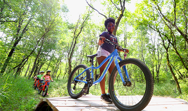 Girl Scouts biking together through a woodland trail