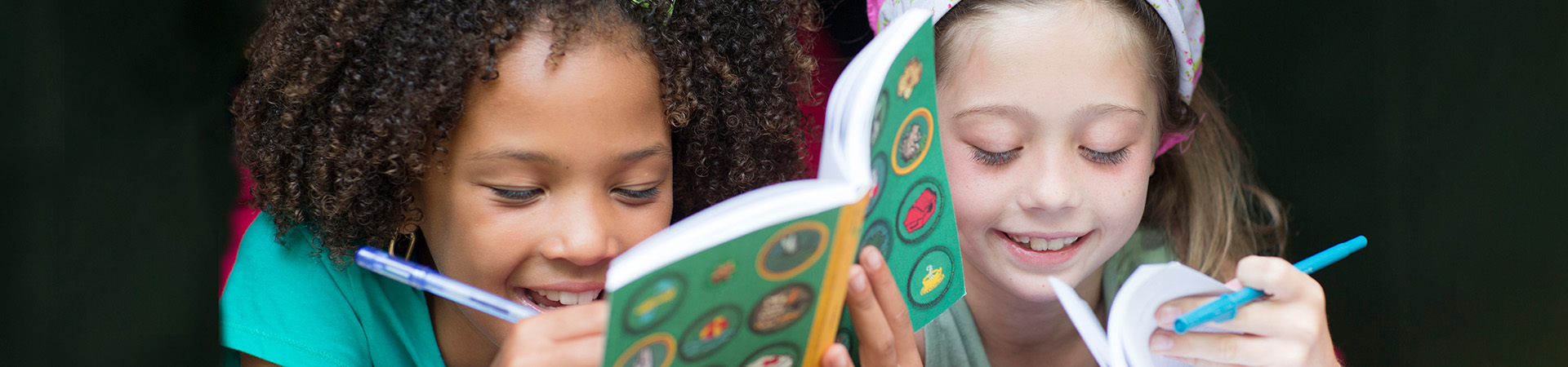  Two Girl Scouts writing in booklets together  