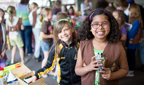 Two Girl Scouts smiling while getting supplies for a wacky inventions activity