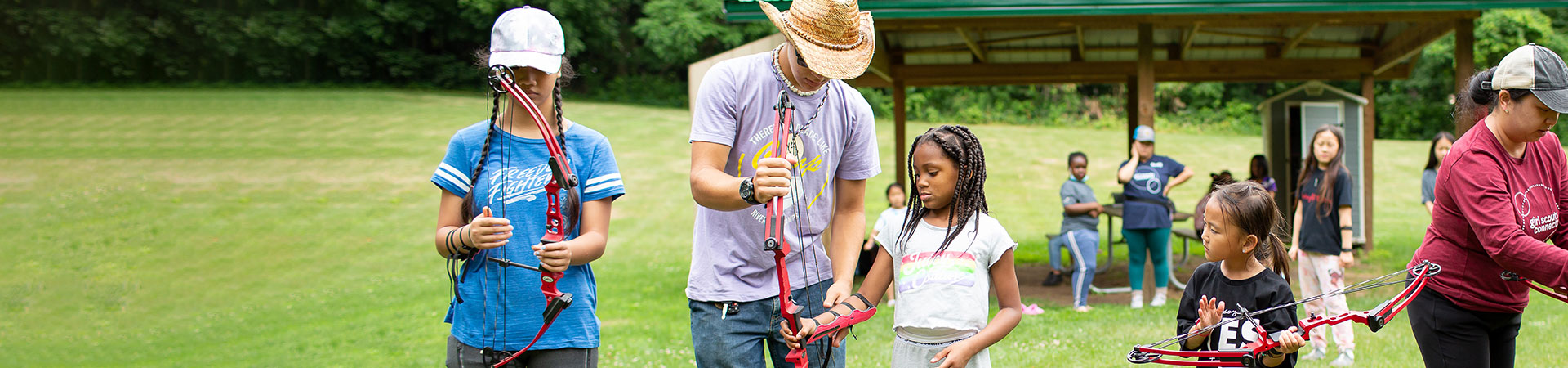  Volunteer in straw hat teaches campers archery  