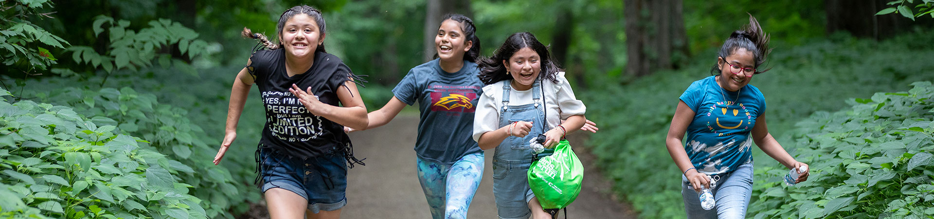  Girls running down a camp trail with smiles 