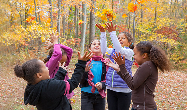 A group of girls throwing Fall leaves into the air