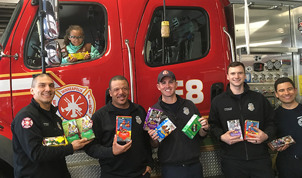 Brownie Girl Scout in a fire truck with firemen holding cookie boxes