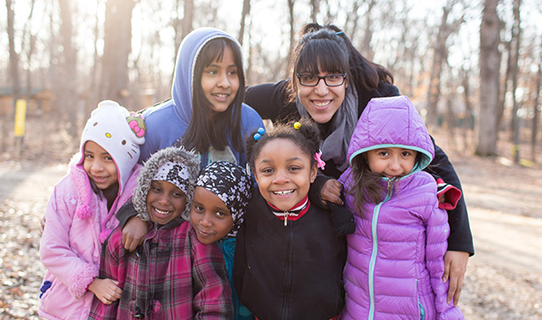 Girl Scouts with troop leader in winter coats smiling together 