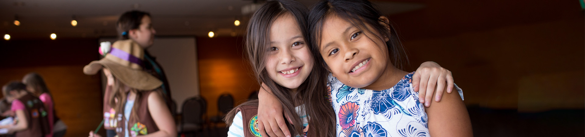  two Girl Scouts with their arms around each other  