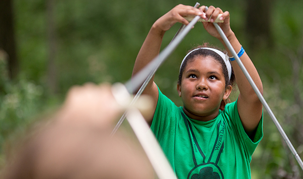 Girl Scout putting up tent support poles at Camp Lakamaga
