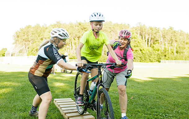 Two volunteers supporting a girl on a bike