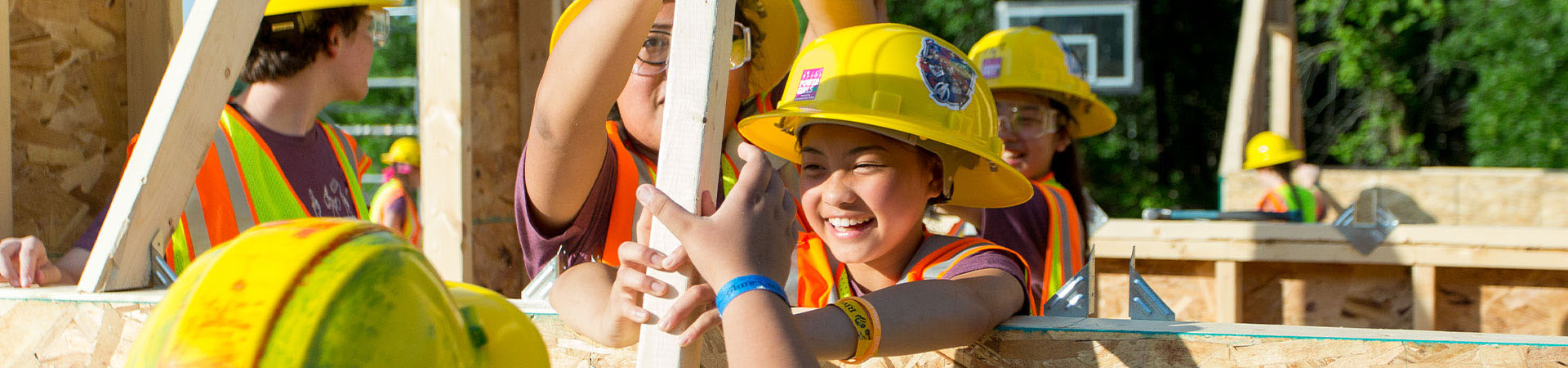  Girl Scouts in hard hats helping to build a structure 